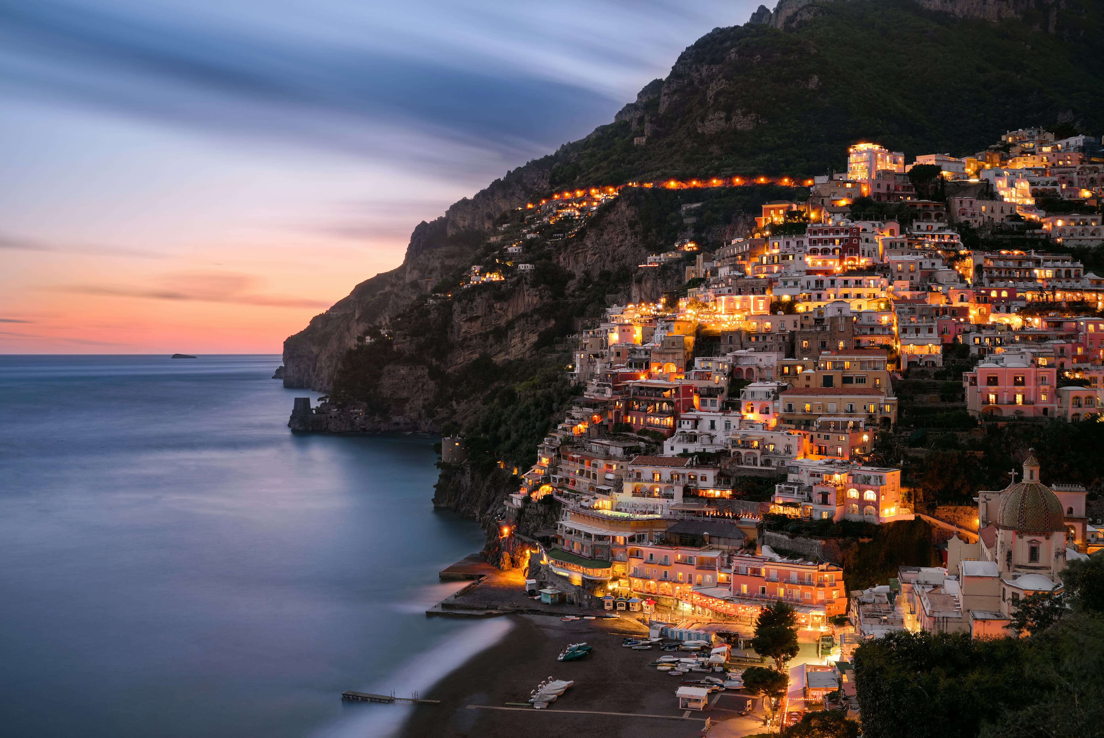 Positano at sunset with lights on the pastel houses